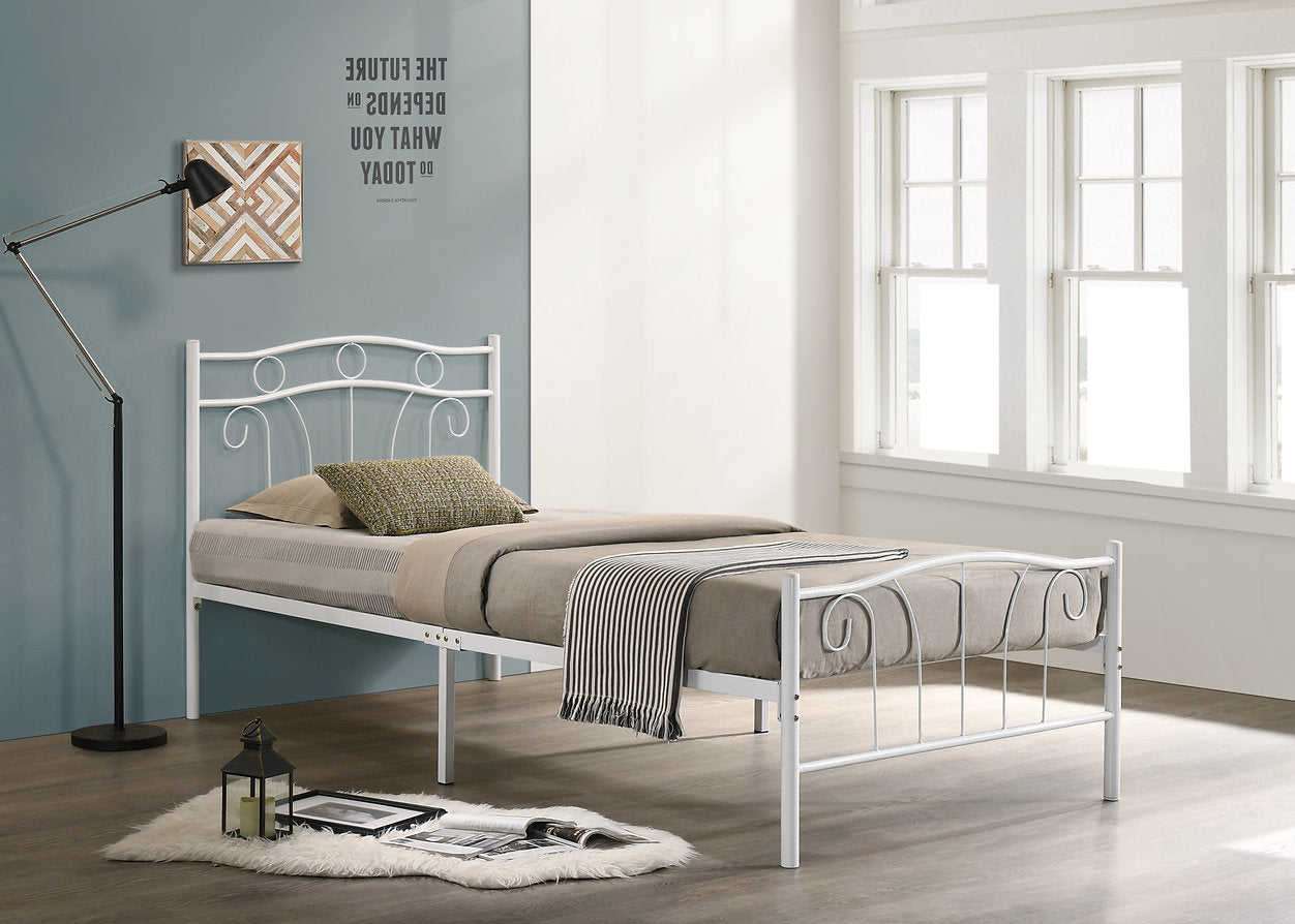 White metal bed frame with bedding in a room with large windows and a lamp.