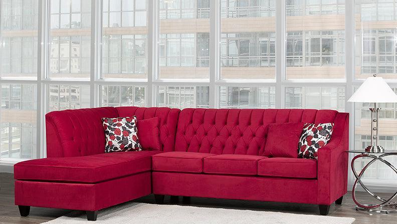 Red sectional sofa with patterned cushions in a room with large windows.