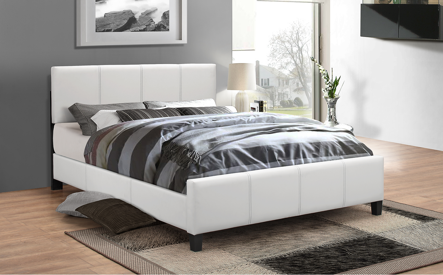 White upholstered bed with striped bedding in a modern bedroom.